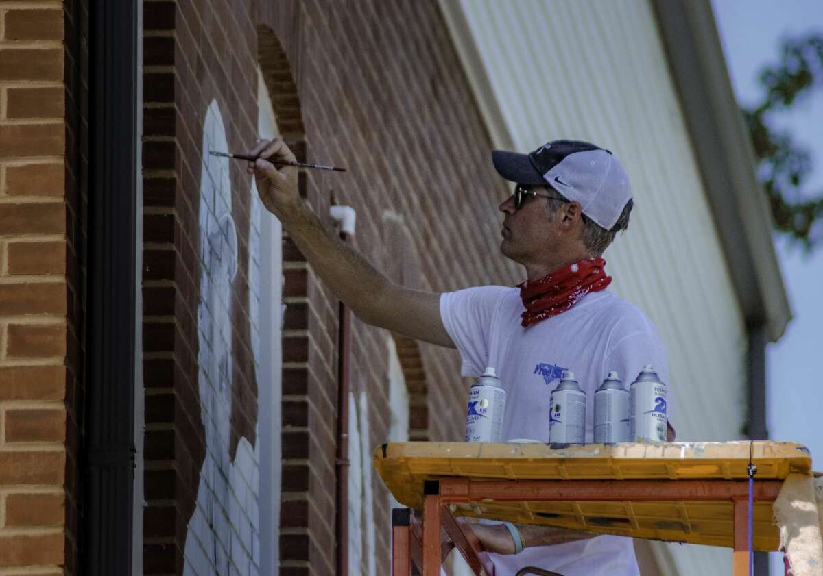 Troy Freeman adds detail to Ken Oberkfell’s portion of a mural put on the east side of the Maryville Heritage Museum.