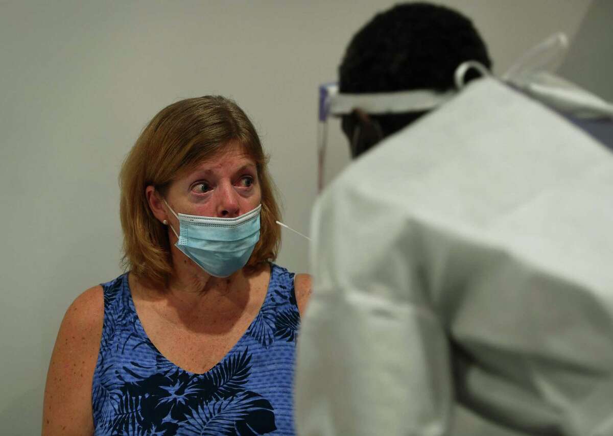Carla Austin, of Tampa, Fla, gets swab-tested for COVID-19 after arriving at Bradley International Airport in Windsor Locks, Conn., on Tuesday, Oct. 6, 2020.