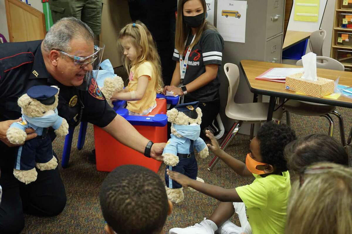 Luis Santiago, Katy Independent School District police officer, left, distributes Teddy Cops bears to special needs students at Wolman Elementary on Thursday, Oct. 8. The Teddy Cops program is designed to teach the children that police officers can be trusted.