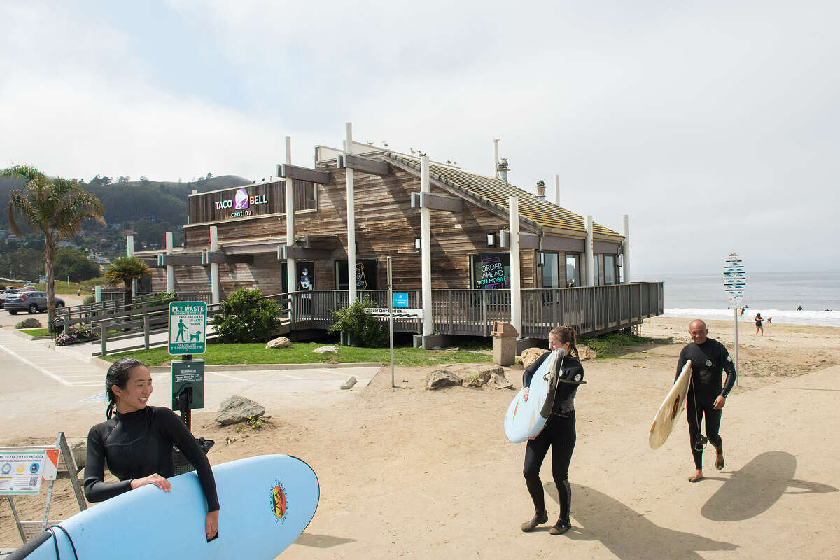 Surfers walk past the Taco Bell Cantina at Pacifica State Beach.