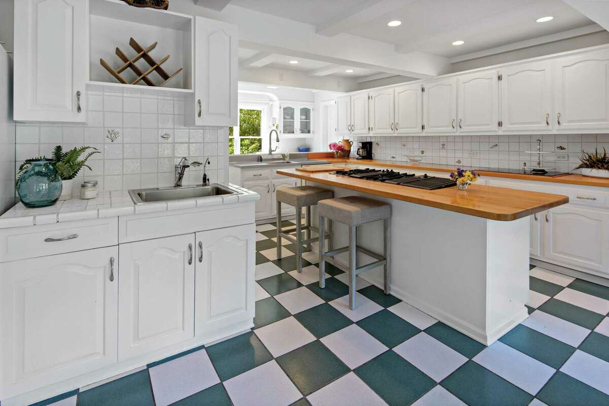 The spacious eat-in kitchen features a center island/breakfast bar, ample counters and cabinets, and walk-in pantry. The front door opens into a two-story foyer with an interior balcony. In the family room there is a brick fireplace and bay window. The spacious eat-in kitchen is at the heart of this home. It features a long center island topped with a wood counter that doubles as a breakfast bar for four or five people. There are also ample counters and cabinets, a walk-in pantry, white ceramic tile backsplash, built-in corner china cabinet, and a preparation sink area that can serve as a wet bar when entertaining. In the dining room there is a wall of windows, French doors to the deck and yard, and two columns that separate it from the formal living room, where there is a marble fireplace and a door to the sun room. The size of the sun room allows for flexible use. The current family has it set up as both a place of relaxation and as a recreation space.