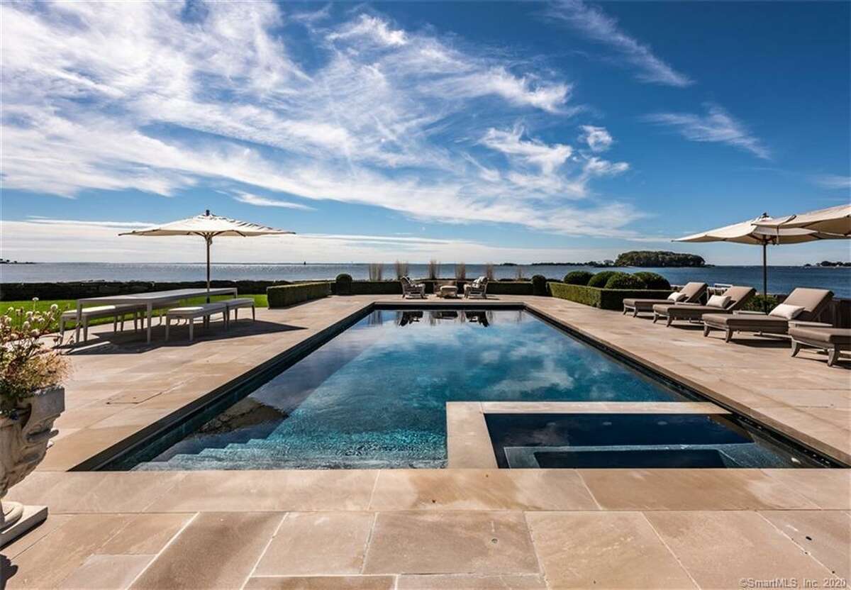 The professionally landscaped property features a Gunite in-ground swimming pool and spa looking over Long Island Sound. The kitchen's features include a center island, marble counters and backsplash, marble tile flooring and a farm sink. The commercial-grade appliances include a Wolf six-burner range with a griddle and pot-filler, and Traulsen refrigerator and freezer. In the large butler's pantry there are marble walls, counters and flooring, a wine refrigerator, glass-front cabinetry, under-cabinet lighting and a farm sink.