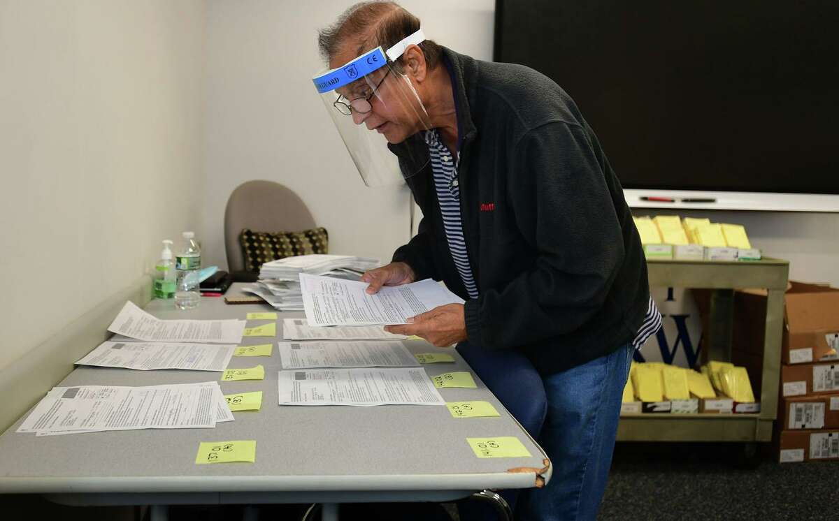 City employees including Ramesh Hingorani verify some of the 11,065 absentee ballot applications the city has received Thurday, October 8, 2020, at city hall in Norwalk, Conn.