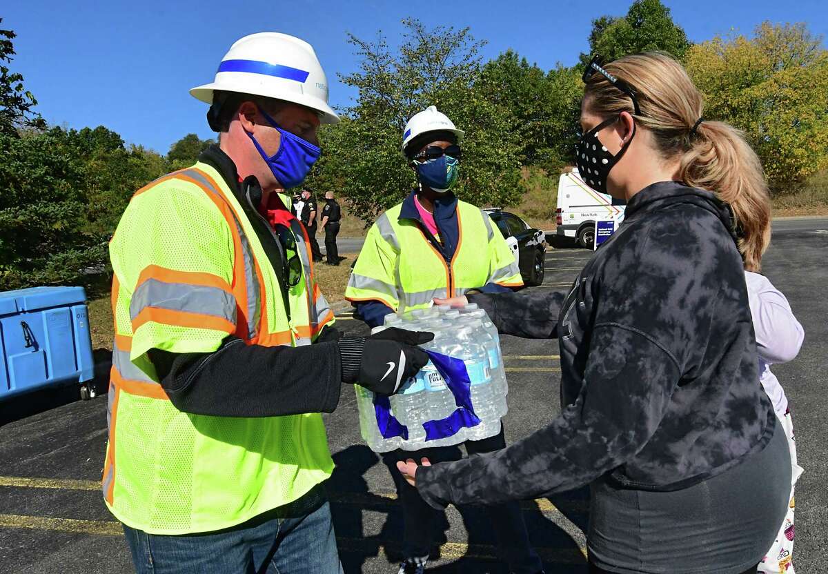 An employee from National Grid hands a case of water to Kristen Padilla of Delmar at the Crossgates Mall parking lot on Friday, Oct. 9, 2020 in Guilderland, N.Y. They also were given a bag of wet ice. Hundreds of people impacted by power outages from Wednesday's storm waited in line for dry ice that never showed up. A limited number of bagged wet ice was given away. (Lori Van Buren/Times Union)