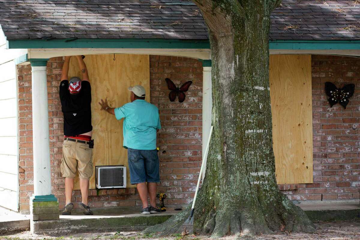 Two men screw in a panel of wood to a window damaged by bullets Monday, Sept. 14, 2020, north of Jersey Village at the home of Sierra Rhodd who was killed late Sunday night.