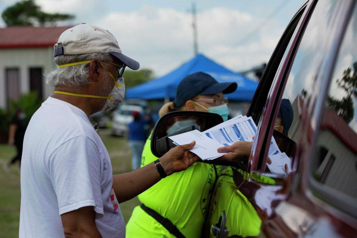Muhammed Nasrullah, 68, hands a voter Texas voter registration applications at a food distribution event, Friday, Sept. 25, 2020, in Houston. Nasrullah has been a voter registrar since 2004.