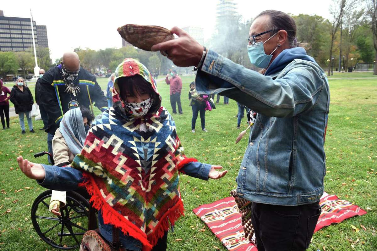 Vanesa Suarez of New Haven is smudged with burning sage by Norman Clement before the start of a celebration of Indigenous Peoples' Day on the New Haven Green on October 12, 2020. Smudging is a ritual is a spiritual cleansing ritual performed by Native Americans.