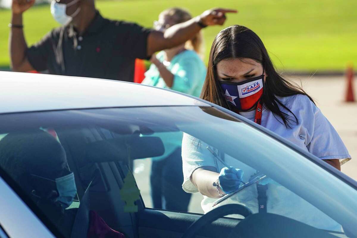 HOUSTON, TX - OCTOBER 07: An election worker accepts mail in ballot from a voter at drive-through mail ballot drop off site at NRG Stadium on October 7, 2020 in Houston, Texas. Gov. Gregg Abbott issued an executive order limiting each Texan county to one mail ballot drop-off site due to the pandemic. (Photo by Go Nakamura/Getty Images)