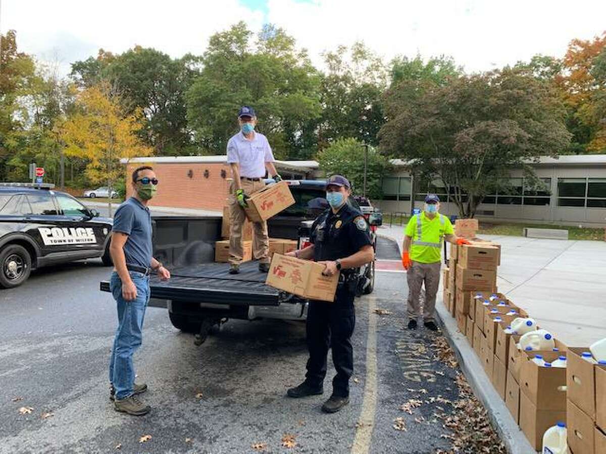 Police officers and Parks and Recreation workers unload food boxes for distribution to Wilton residents in need on Oct. 13, 2020.