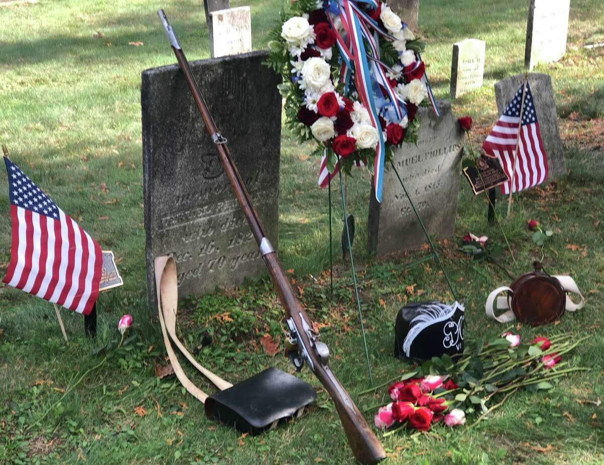 The Roger Sherman Chapter, Daughters of the American Revolution held a grave marking dedication ceremony for the Revolutionary War services of two African-American soldiers from New Milford, Samuel Phillips and Jeruel Phillips Sunday at Center Cemetery in town. Above, a soldier's accoutrements - a helmet, a cartridge box, a musket and a canteen - are placed in front of their gravestones by Lt. Russ Kenney of the 6th Connecticut Regiment.