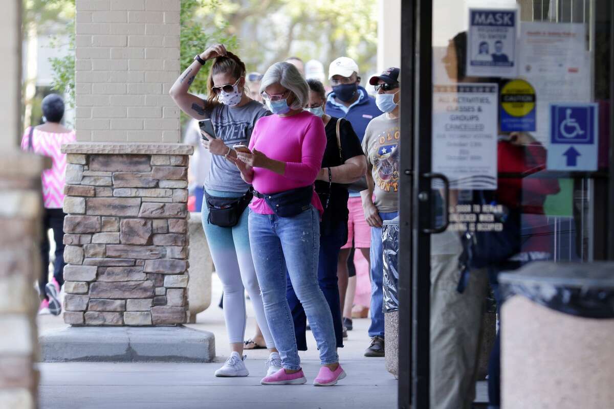 Voters wait near the entrance in a line that snakes around the corner of the building outside of the Trini Mendenhall Community Center as early voting begins Tuesday, Oct. 13, 2020 in Houston, TX.