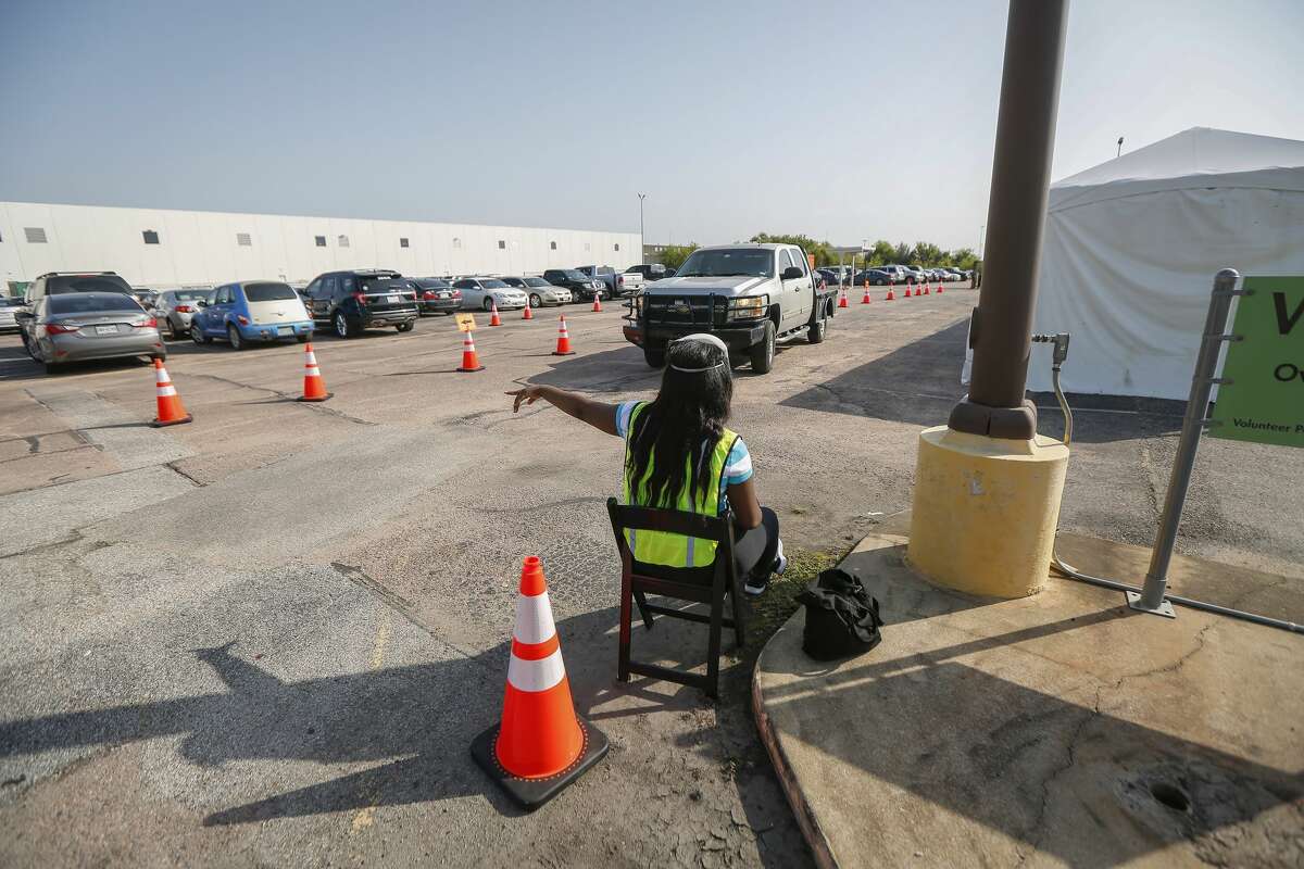 A Voter Assistant aids a drive-thru voter with exiting at the Houston Food Bank, which is operating an early voting site for the first time Tuesday, Oct. 13, 2020, in Houston.