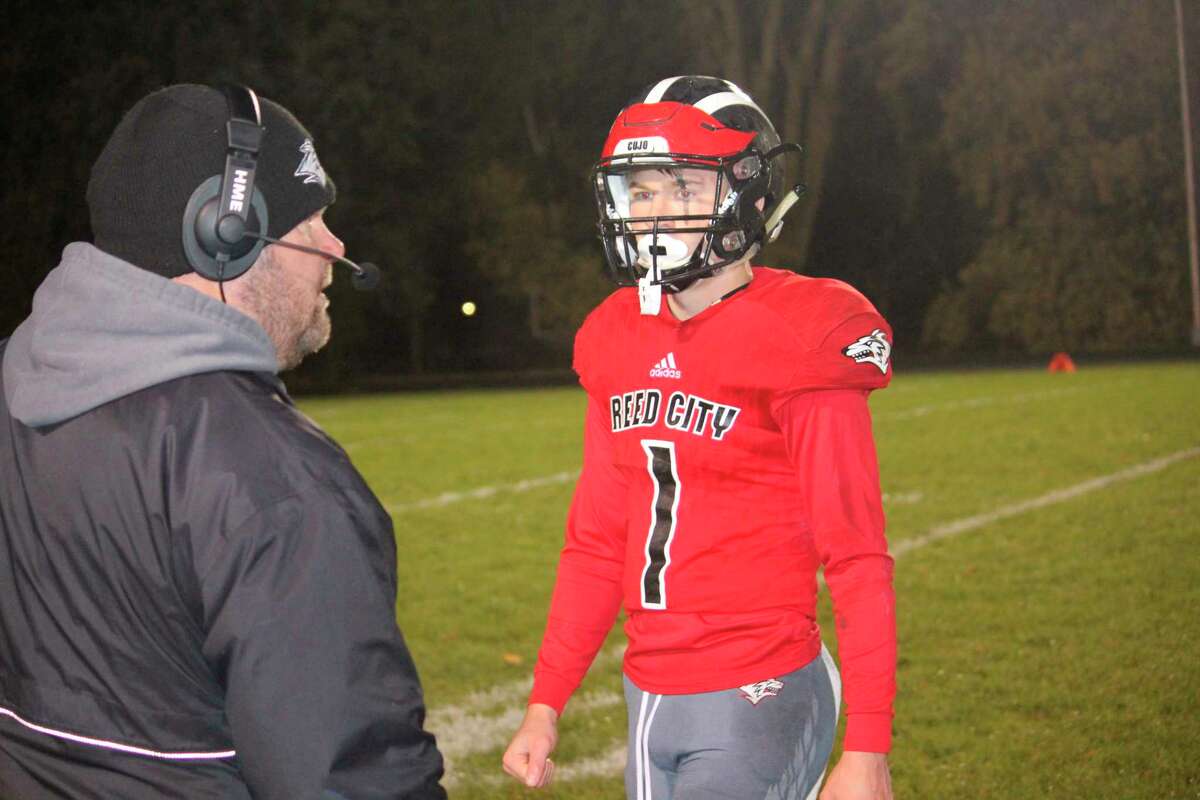Reed City's football coach in 2018, Monty Price (left), confers with his son and quarterback Jackson Price during a game. (Pioneer file photo)