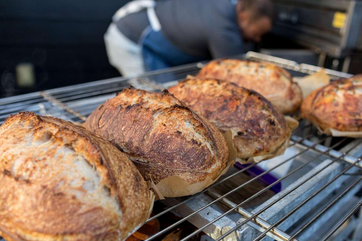 Azikiwee Anderson of Rize Up Sourdough removes loaves from his S.F. backyard oven and places them on a cooling rack.