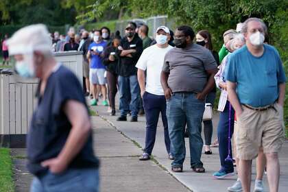 People wait in a long line outside at the Metropolitan Multi-Services Center, 1475 W. Gray St., during the first day of early voting Tuesday, Oct. 13, 2020 in Houston. The line wrapped around the baseball field.