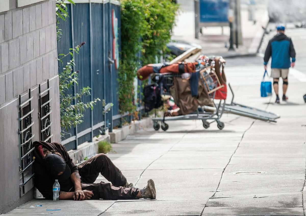 A man lies, passed out after getting high on a sidewalk near City Hall in San Francisco.