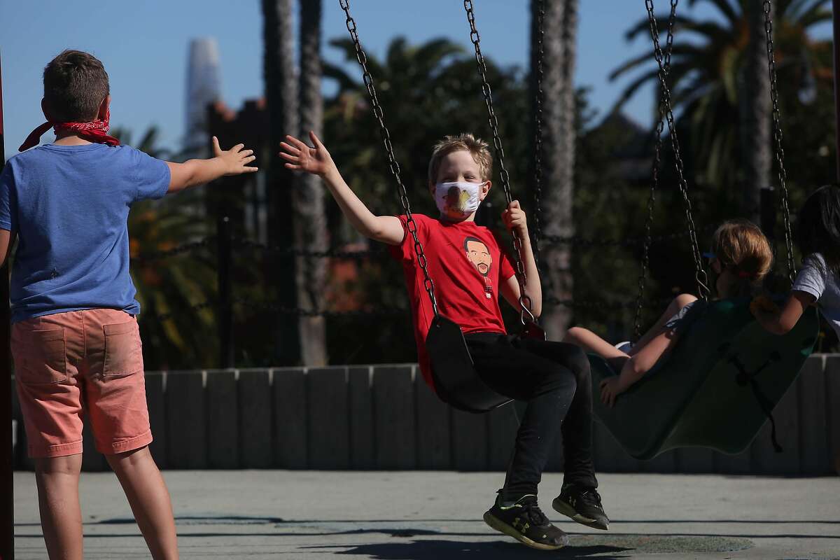 Desi Ach (left), 10, and Matty Taylor, 10, greet each other at the swings in the reopened Helen Diller Playground in Dolores Park.