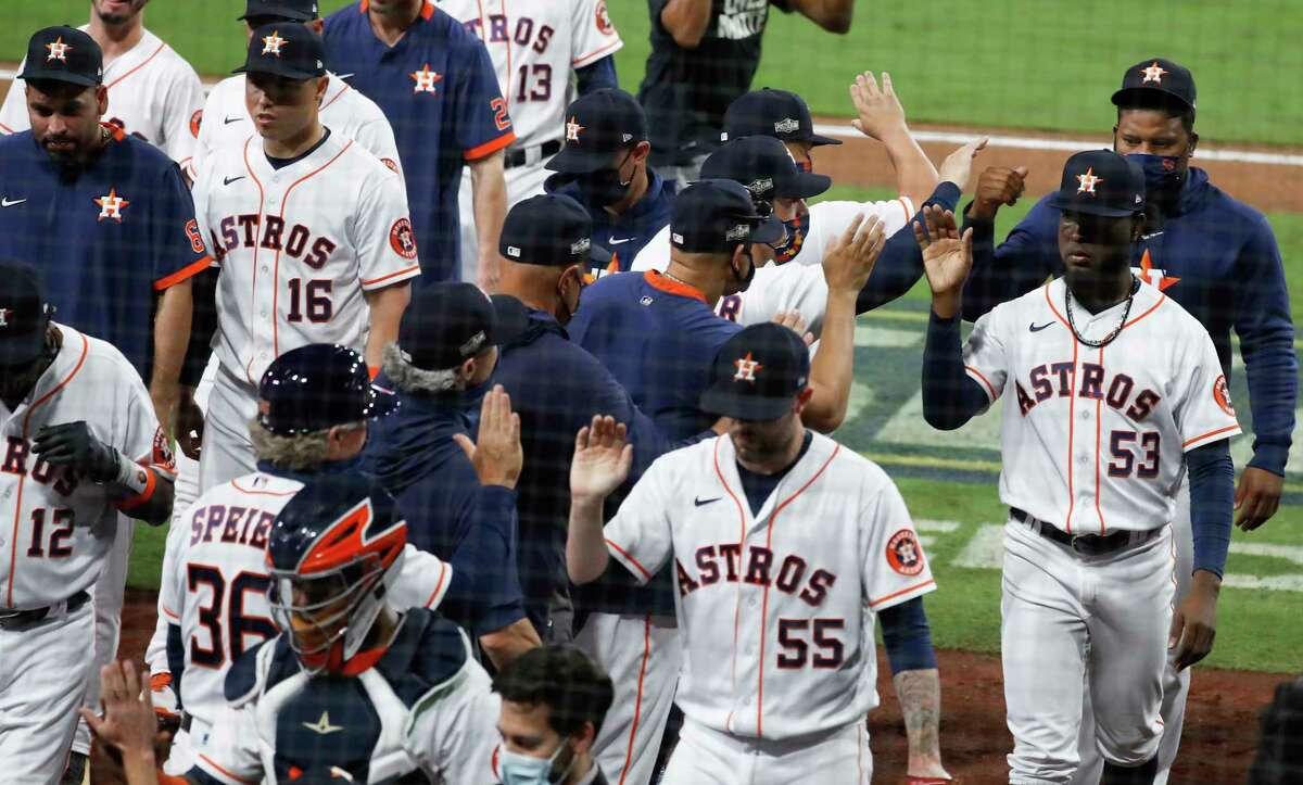 Houston Astros players high five after the Astros beat the Tampa Bay Rays 4-3 to stay alive in the American League Championship Series at Petco Park Wednesday, Oct. 14, 2020, in San Diego. The Rays lead the best-of-seven series 3-1.