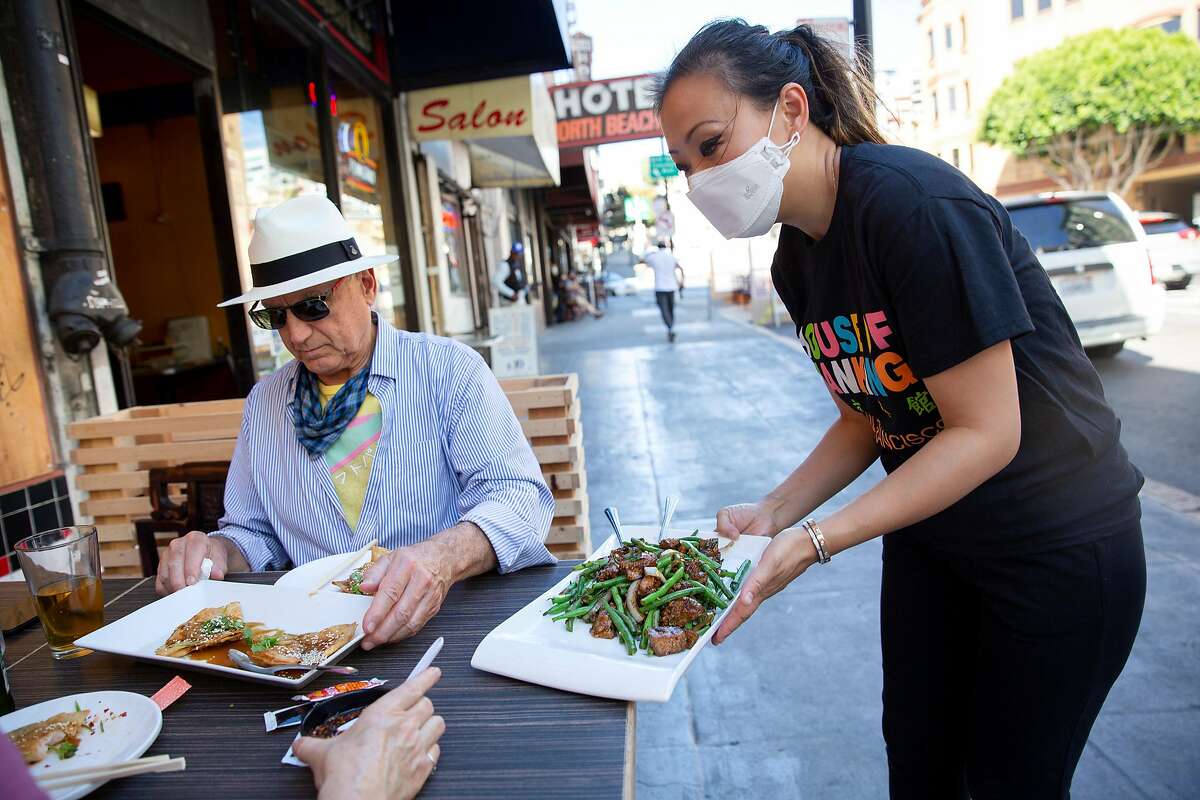 Kathy Fang brings food to customers dining outdoors at House of Nanking restaurant in San Francisco.