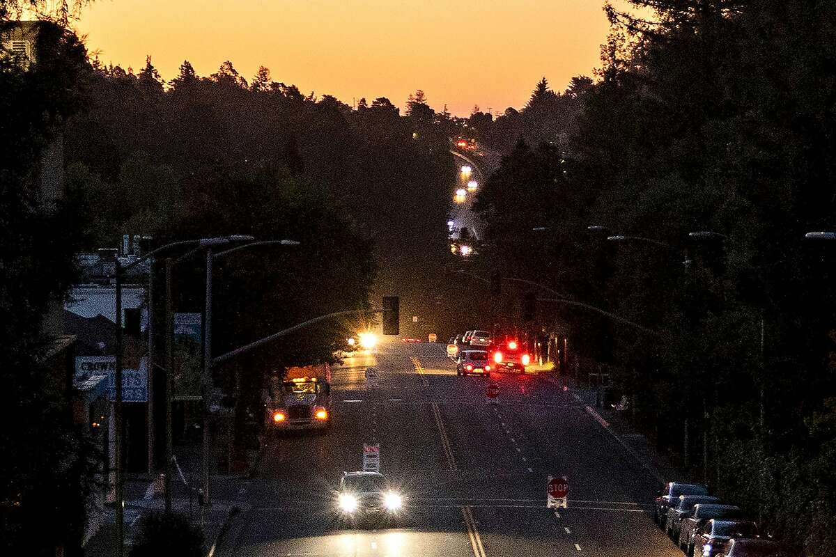 Cars drive along Mountain Boulevard in Montclair Village that was left in the dark after PG&E shut off power to the area.