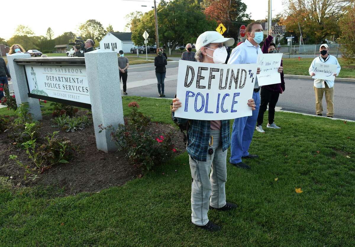 Sue Huybensz, center, of Deep River and others gather outside Old Saybrook police headquarters to protest an incident involving the local officers and a resident with Down Syndrome. Mark Hand, a member of the Citizens’ Police Review of Old Saybrook, which organized the event, said the group is concerned about “the lack of transparency with the police commission and their oversight of the Department of Police Services.” The group, which formed several months ago, organized the rally within 24 hours of the incident with the Roy family. “Abuse of authority by the police department and the chief, as well, is just not something citizens want to sit by and watch and accept,” Hand said. “We want to stress our pain and outrage and hope and demands for change,” he added. Roy had alleged in a Facebook post that police came to her family’s cottage after receiving a report that a male driver had stolen a street sign. The officers “aggressively” questioned her brother, Roy alleged, adding that she told the officers he could not be the person they were seeking as he is unable to drive.  