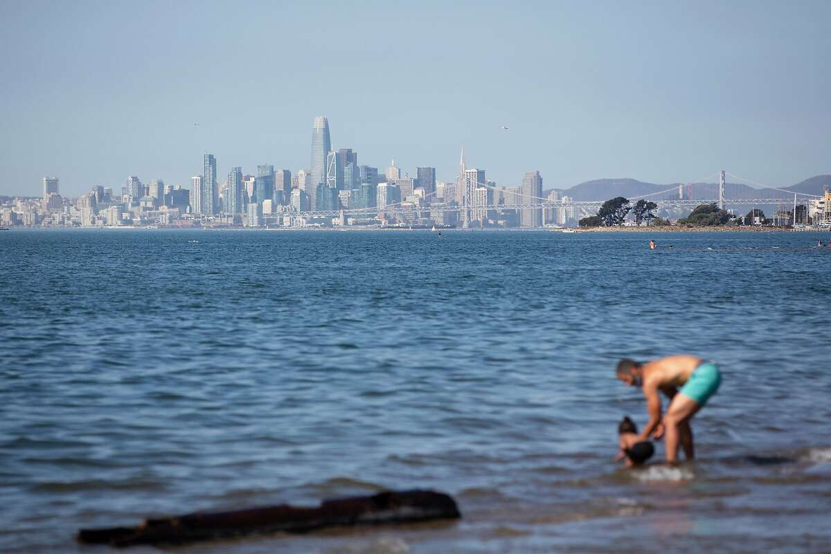 With the San Francisco skyline in the background, people play in the water at Crown Beach in Alameda during the heat wave.
