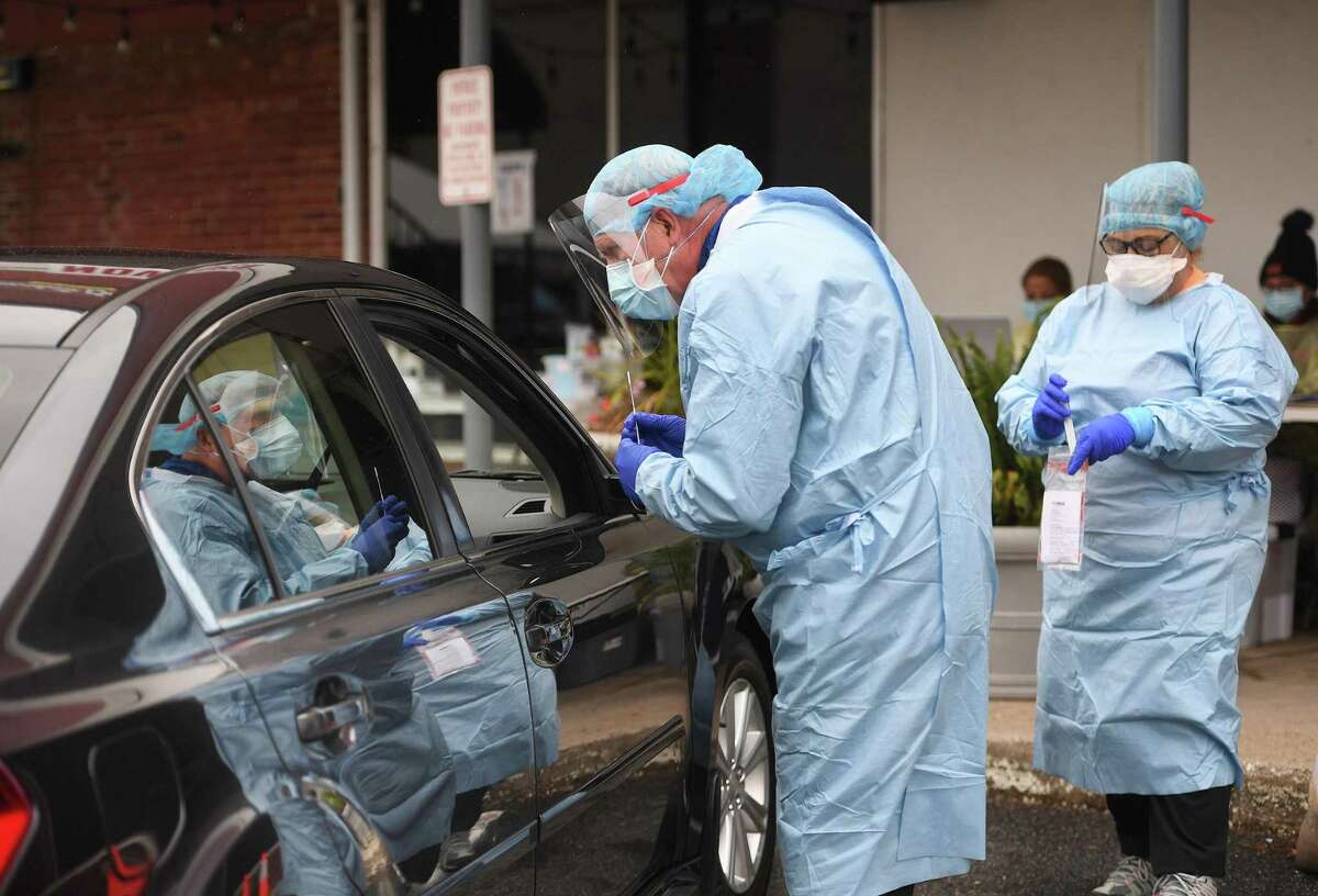 Dentist Tom McManus and dental hygienist Ana Dacosta administer a COVID-19 swab test outside the Community Health Center of Danbury on Delay Street in Danbury last week.