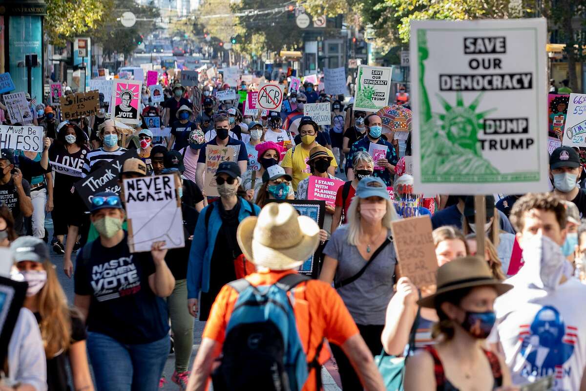 Thousands march down Market Street with masks and signs during the Women's March from Civic Center Plaza to the Embarcadero in San Francisco on Saturday.