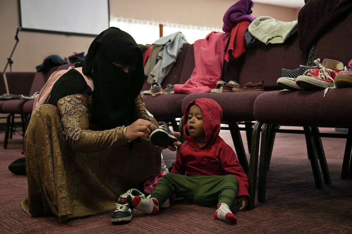 Minara Binti Mustaq Ahmed tries shoes on her son, Mohamad Yasoddin Mohamad Ayas, 1, during the Center for Refugee Services winter coat distribution at Resurgent church in San Antonio on Friday, Oct. 16, 2020. They are Rohingya refugees from Myanmar (formerly Burma), who arrived in the United States in December of 2019.