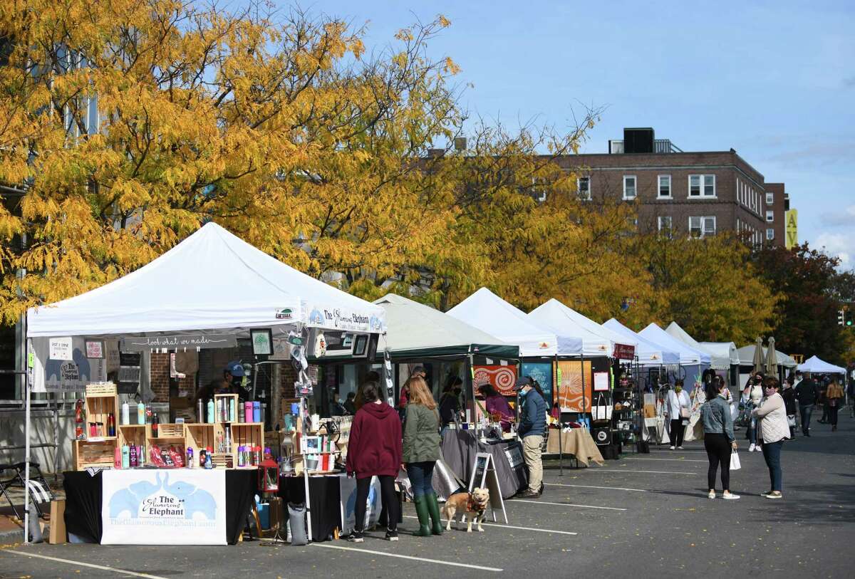 Folks browse artists' work at the Stamford Downtown Arts & Crafts on Bedford Street event in Stamford, Conn. Sunday, Oct. 18, 2020. The arts and crafts show and sale returned for a second time as Bedford Street closed down to traffic to allow folks to browse more than 20 stands and enjoy outdoor dining with extended outdoor patio cafes. Local and regional vendors displayed a variety of work including paintings, photography, sculpture, candles, garments, jewelry, hats and gloves, and much more.