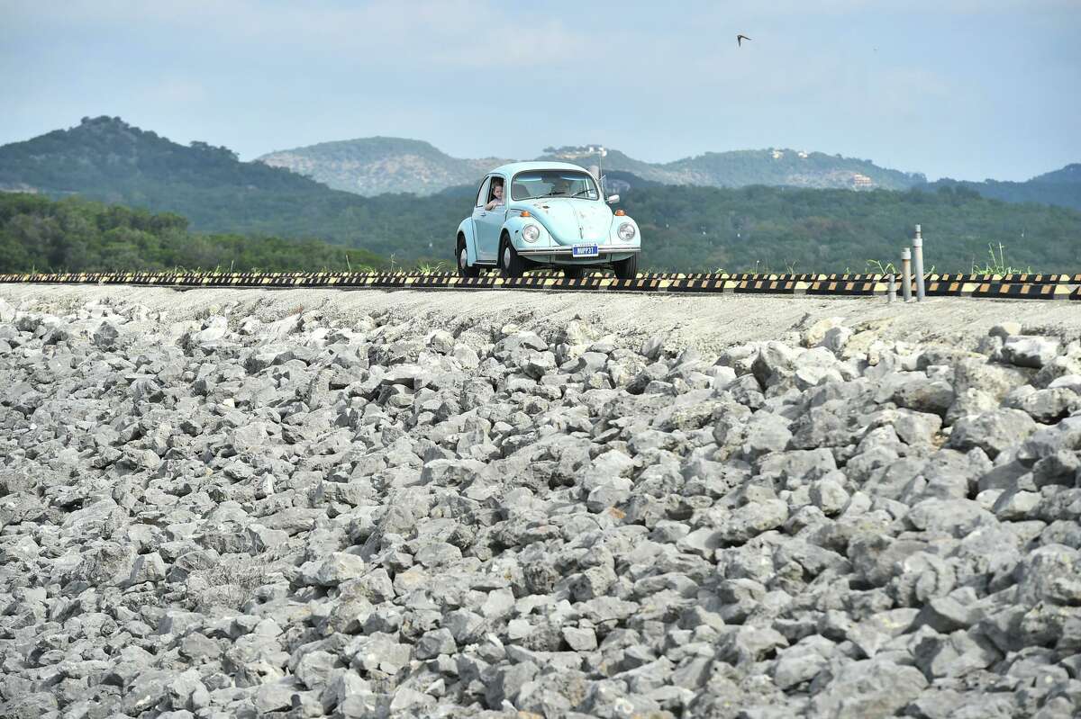 A car drives across the Canyon Lake Dam on Sunday. The Dam Community Alliance normally puts on a car show as a way to raise funds for projects and improvements to the dam, lake and surrounding parks.