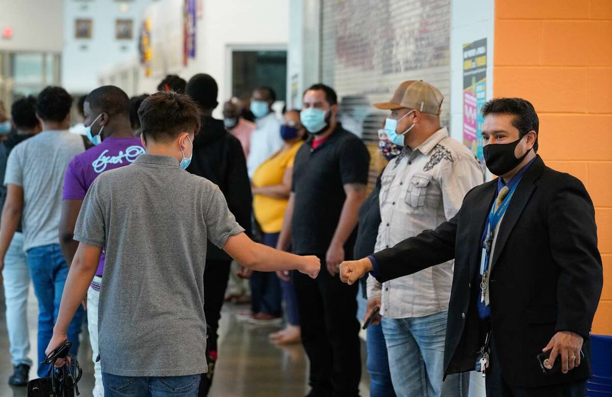 Francisco Rivera, staff member, right, gives a fist bump as students return for the first day of in-person classes at Booker T. Washington High School, Washington High School 4204 Yale St., Monday, October 19, 2020 in Houston.
