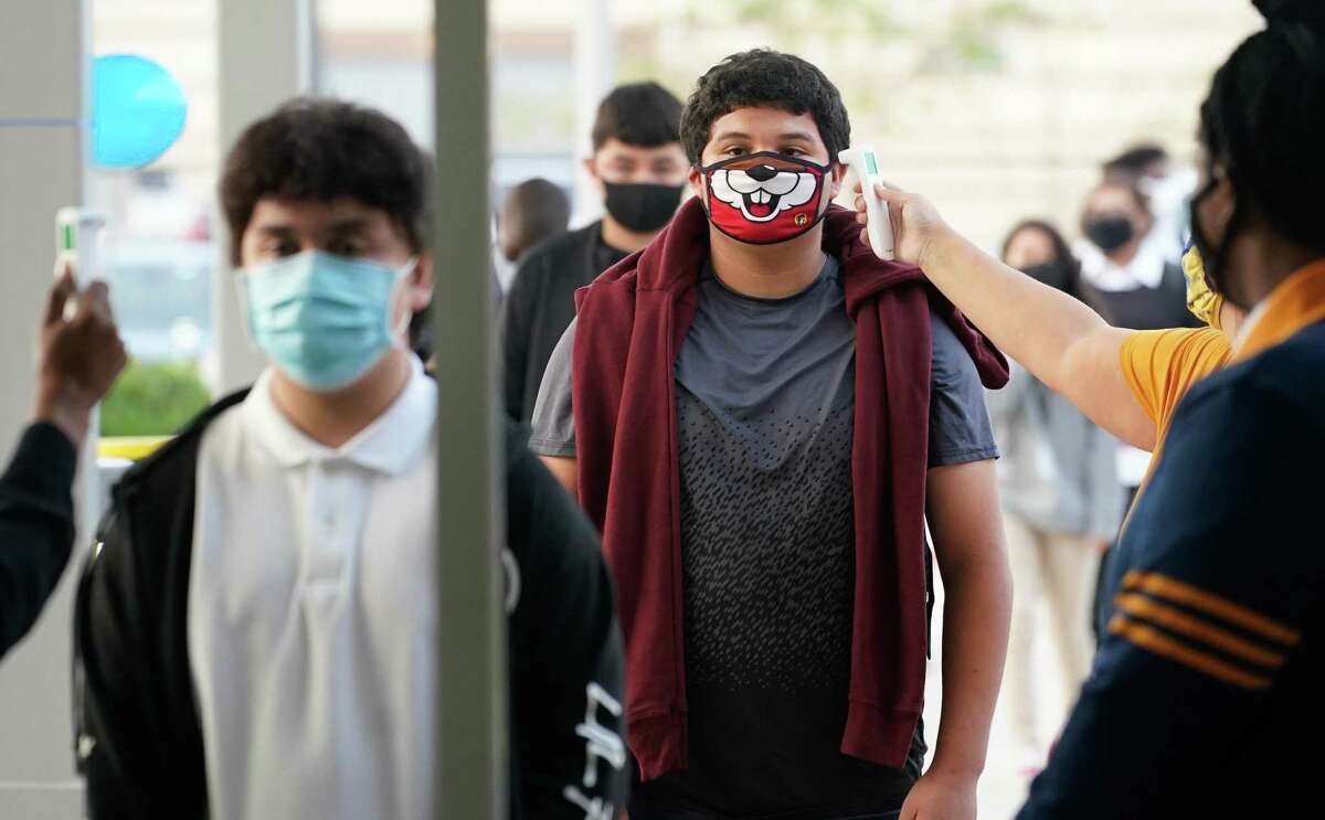 Booker T. Washington High School junior Enrique Alpizar, right, has his temperature taken as he and other students return for the first day of in-person classes at the Houston ISD school Monday. District officials estimated about 40 percent of the roughly 196,000 students enrolled will attend in-person classes.