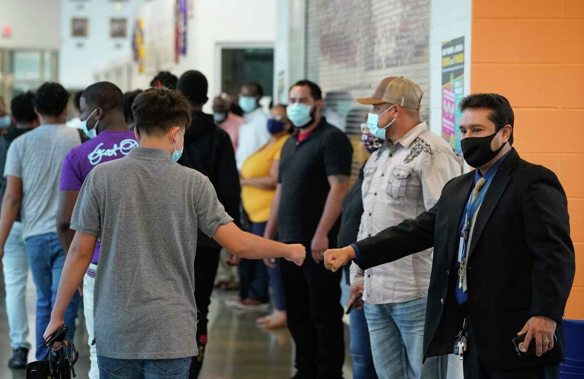 Booker T. Washington High School staff member Francisco Rivera, right, gives a fist bump as students returning for the first day of in-person classes at the Houston ISD campus Monday.