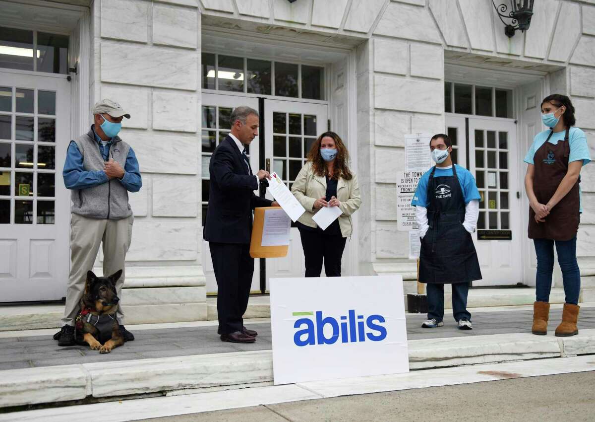 Greenwich First Selectman Fred Camillo presents Abilis President and CEO Amy Montimurro with a declaration marking October National Disability Employment Awareness Month beside the First Selectman's Advisory Committee for People with Disabilities Chairman Alan Gunzburg, left, and Abilis clients Danny Clarke and Dana Verlander outside Town Hall in Greenwich, Conn. Monday, Oct. 19, 2020. First Selectman Camillo acknowledged the work that the nonprofit Abilis is doing to get employment for its special needs clients through programs at the Greenwich Hospital, Greenwich Library, and Coffee for Good cafe.