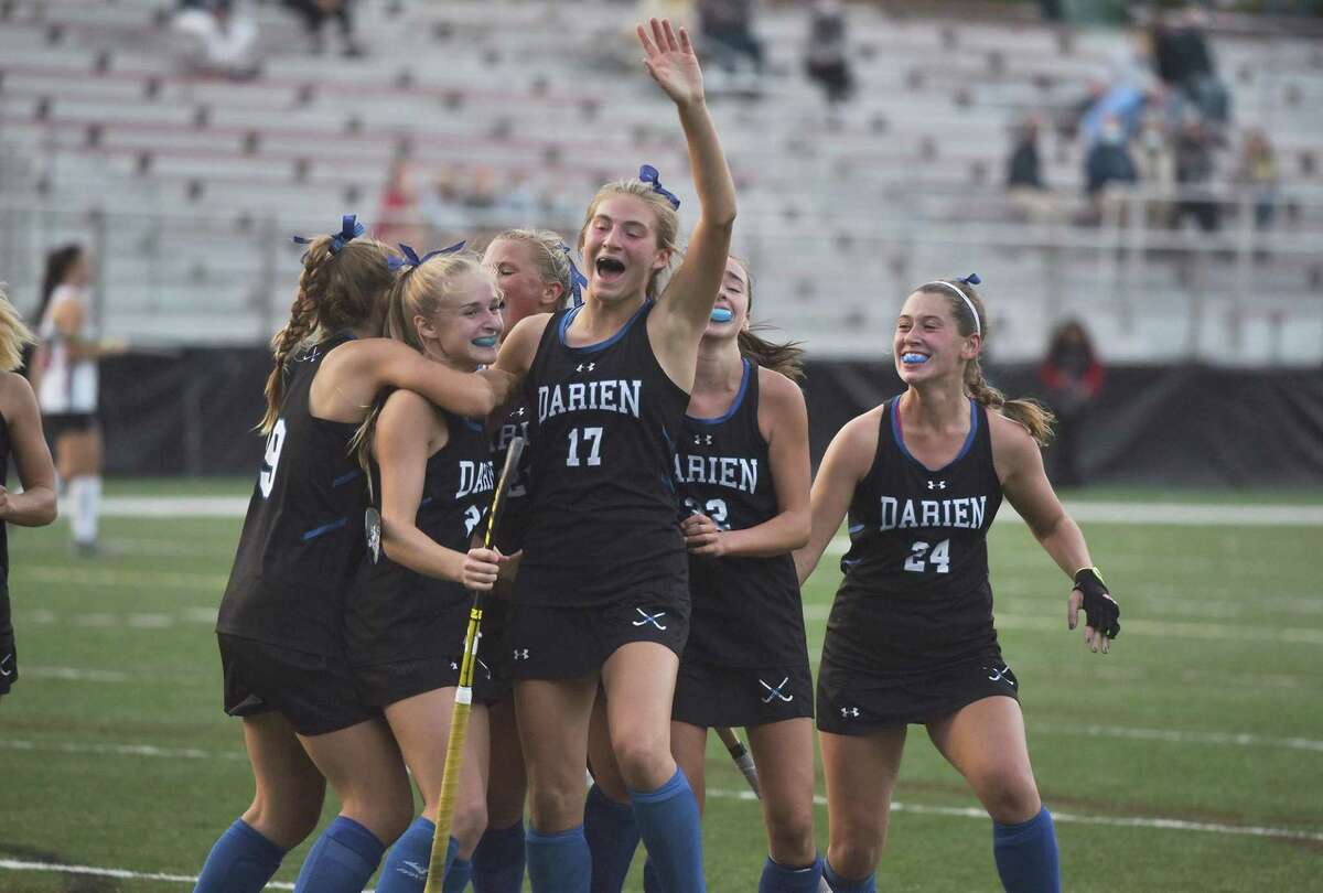 Darien field hockey players, including Blake Wilks (23), Morgan Massey (17), and Lindsey Olson (24), celebrate a third-period goal against New Canaan at Dunning Field on Monday.
