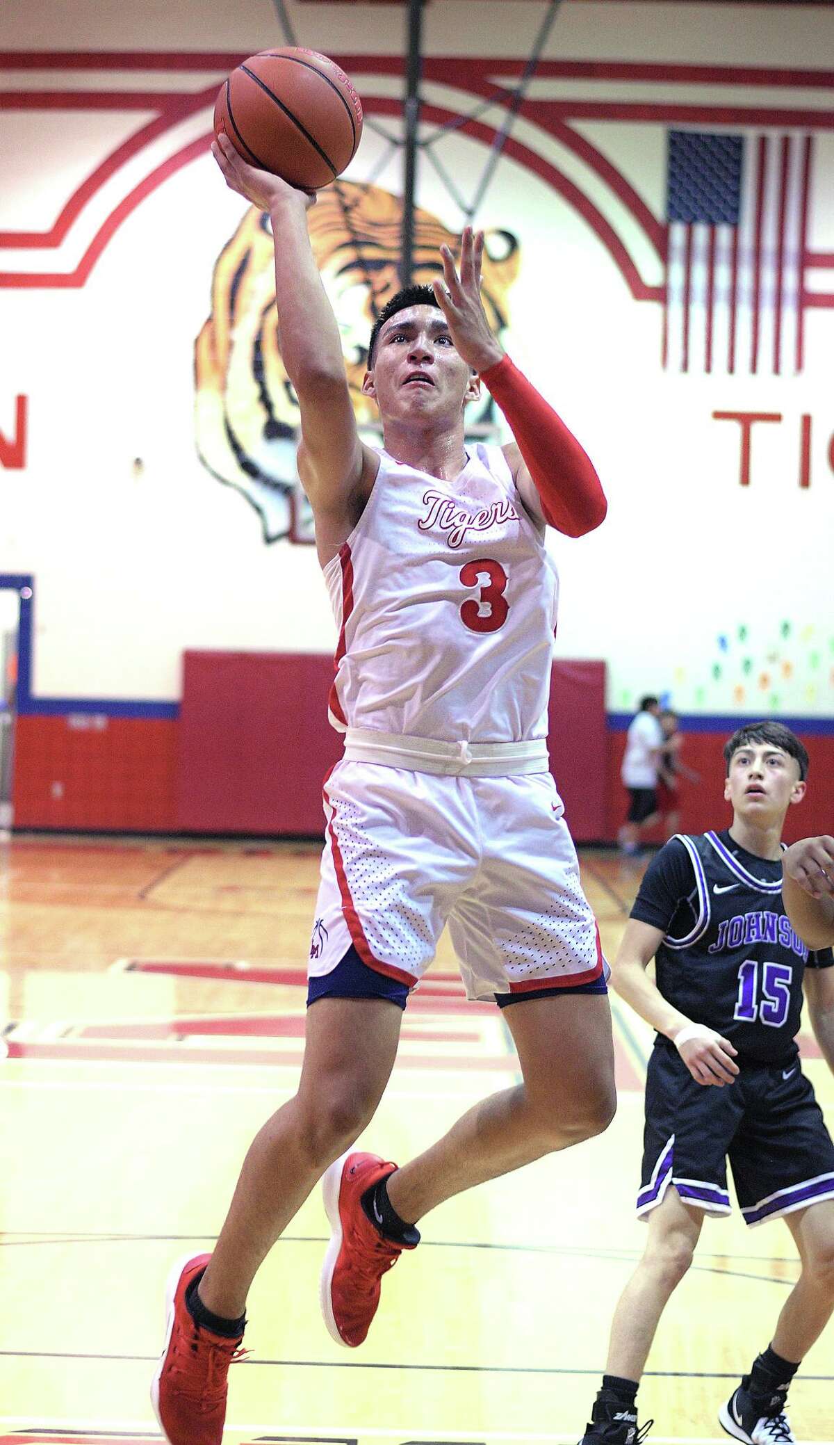 Kevin Garcia drives to the basket for the Martin Tigers as Chris Merino follows the action for the LBJ Wolves Tuesday, November 19, 2019 at the Roberto J. Flores Gymnasium at Martin High School.
