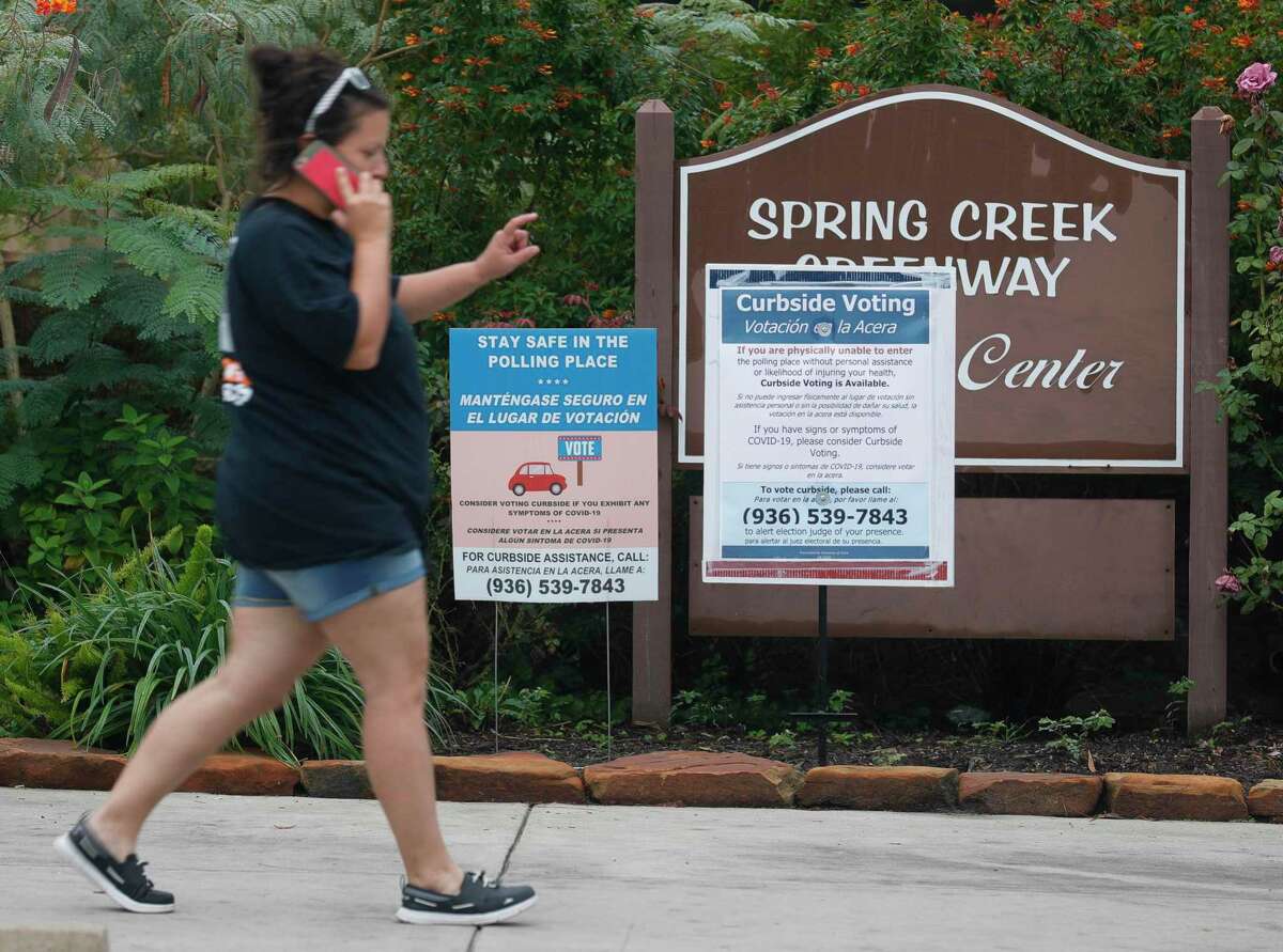 A woman walks past a curbside voting sign at the Spring Creek Greenway Nature Center, Tuesday, Oct 20, 2020 in Spring. Montgomery County commissioners unanimously approved opening early voting centers at the nature center and East Montgomery County Court Annex during a special meeting Monday, Oct. 19, as voter turnout continues to sore surpassing 2016 totals by just over 4,100 in the first five days of early voting.