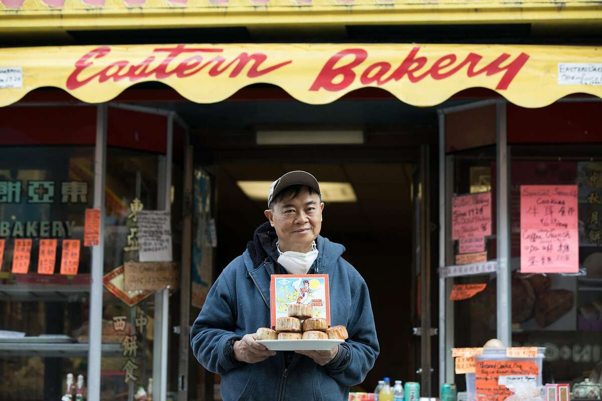 Eastern Bakery owner Orlando Kuan holds some of his bakery's freshly made lotus mooncakes in front of his store on Grant Avenue in Chinatown in San Francisco on Oct. 7, 2020.