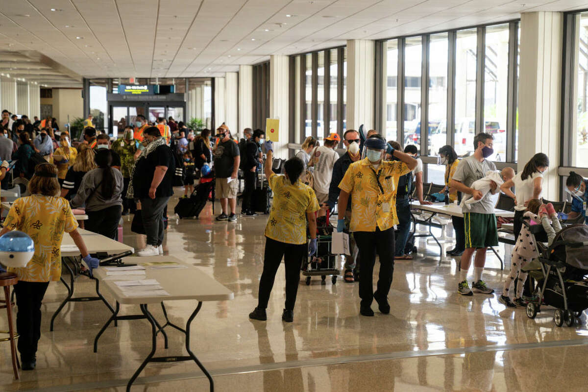 State officials at Honolulu International Airport check to be sure all arriving visitors and residents alike have answered a health questionnaire, had their temperatures taken and shown proof of a negative COVID test.