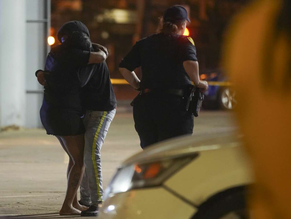 Onlookers comfort while Houston Police investigate a triple homicide at DD Sky Club in the 2100 block of Chenevert Street in Houston on Tuesday, Oct. 20, 2020. At least two shooters were involved in the incident during an open-mic night that left three people dead and one wounded.