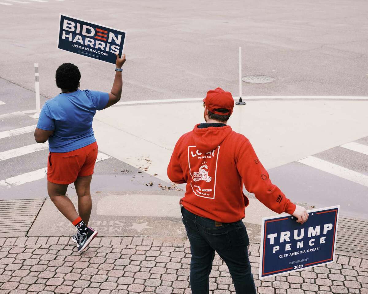Tamika Morris, 47, a volunteer with Pinellas for Biden, waves a sign at passing cars next to Pinellas GOP volunteer Robby Thurston, 38, at the supervisor of elections office in downtown St. Petersburg, Fla., on Oct. 19, the first day of early voting in Pinellas County.