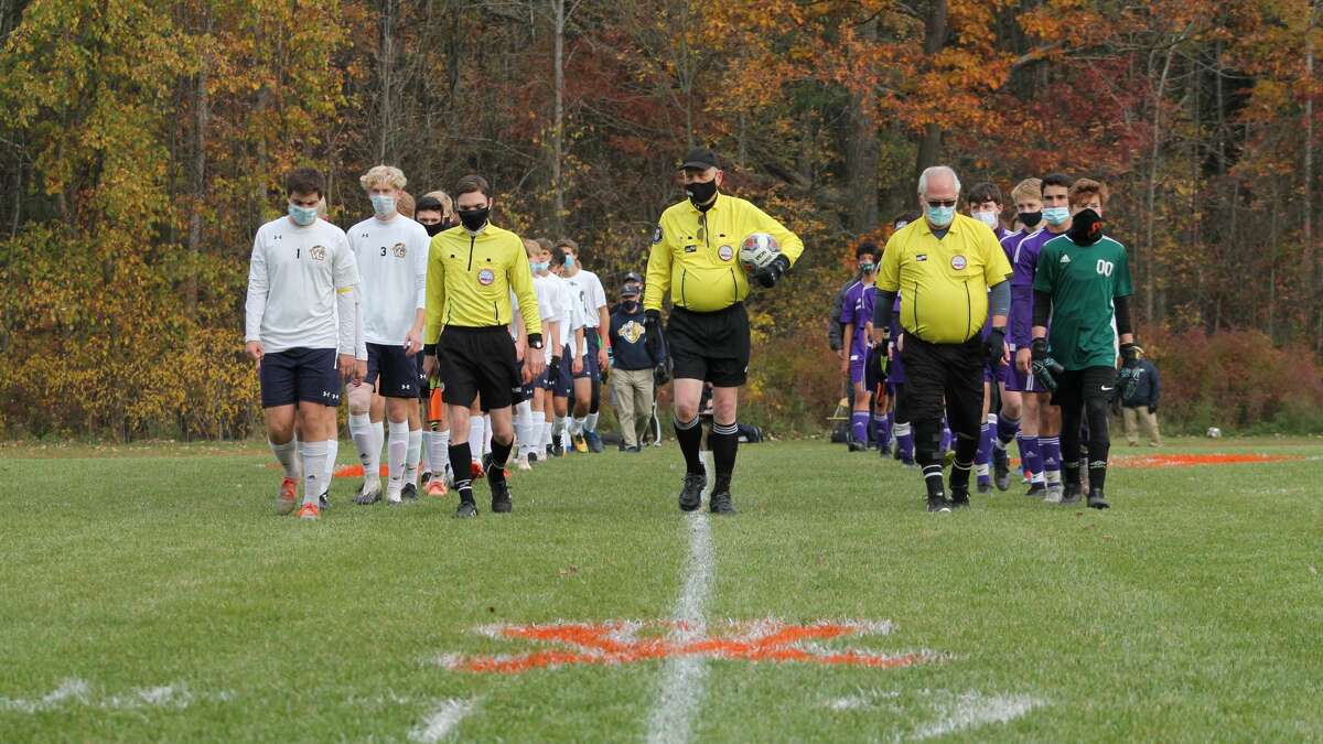 Calvary Baptist (right), Saginaw Valley Lutheran (left) and the referees walk down the middle of the Kings' field before a Division 4 district semifinal on Oct. 20. CBA won 4-2.