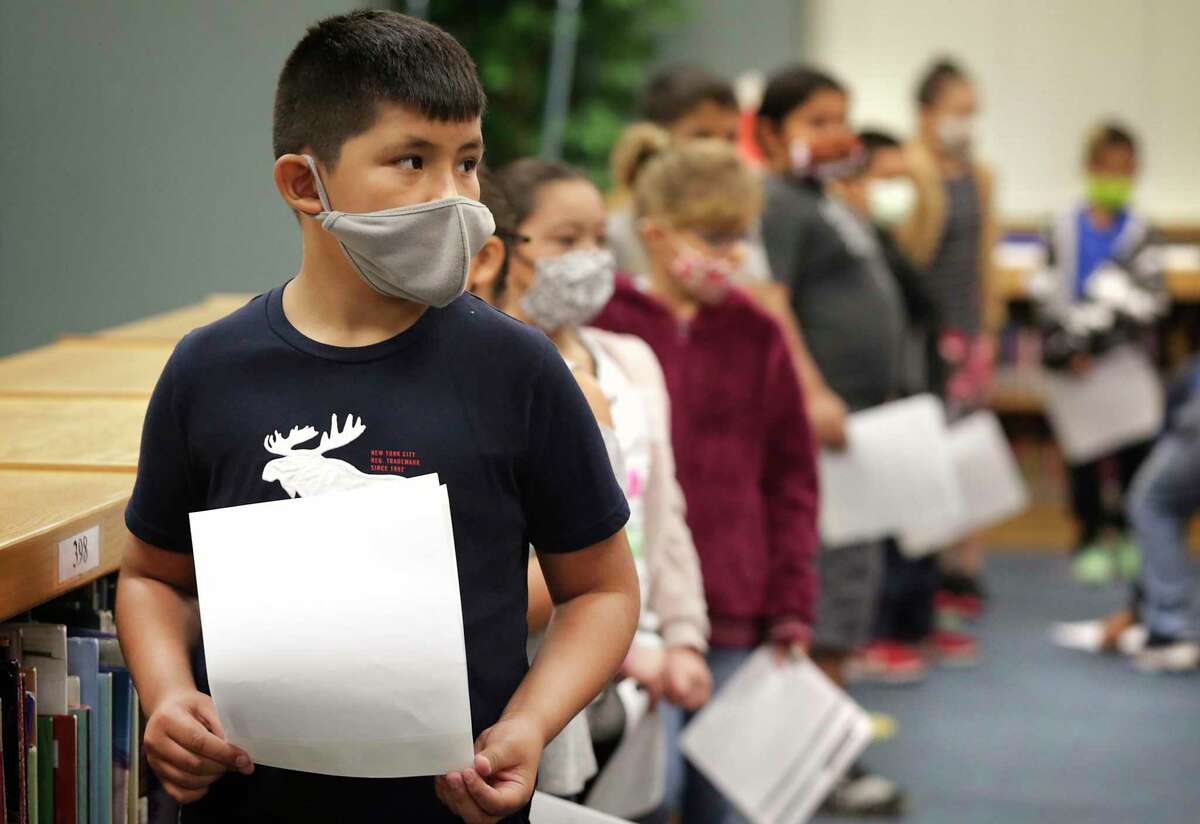 Technicians from Community Labs test staff and students at Barrera Veterans Elementary School in Somerset ISD for the coronavirus Wednesday. Matthew Gallegos, a third grader at the school, holds his permission slip in line with other students.