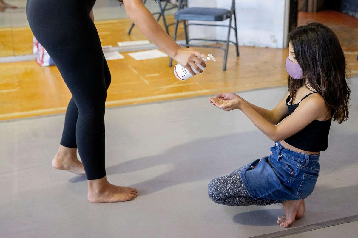 Pod teacher Emma Miller distributes hand sanitizer to students before the start of a Taiko drumming class offered as part of an arts pod organized by Dance Mission Theater in the Mission District of San Francisco, Calif. Tuesday, October 13, 2020. Several arts pods have popped up in San Francisco, funded by foundations for low-income kids since COVID-19 pandemic has shut down regular in-person schooling.