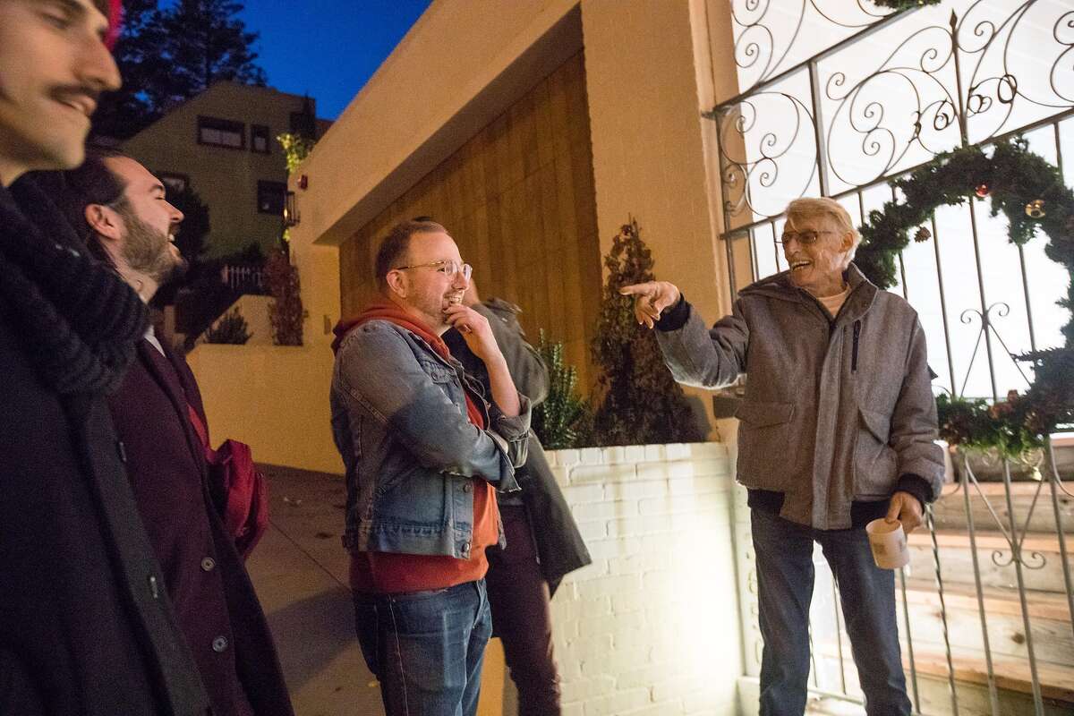 Tom Taylor, far right, speaks with visitors outside his holiday-decorated house in San Francisco on Dec. 15, 2019.