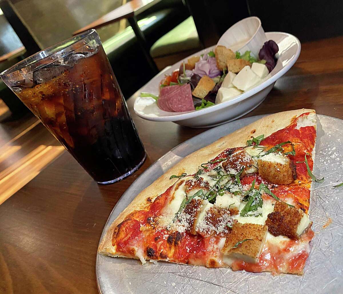A pizza combo includes a slice of pizza such as this daily special of Chicken Parmesan (fried chicken, red sauce, basil, Parmesan cheese and housemade mozzarella), a soft drink and a salad for $9 at Bootleggers Pizza Parlor in New Braunfels.