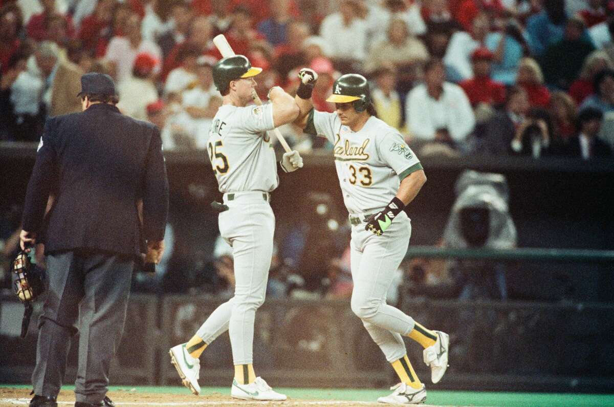 Jose Canseco and Mark McGwire of the Oakland Athletics celebrate Canseco's home run during Game 2 of the 1990 World Series against the Cincinnati Reds at Riverfront Stadium in Cincinnati, Ohio.