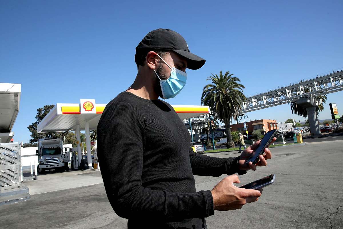 Uber driver Jorge Torres, 29, looks at his phones for ride pickups at a Shell gas station near the Oakland International Airport in October. Uber may end a feature that let drivers see destinations upfront and set pricing for rides.