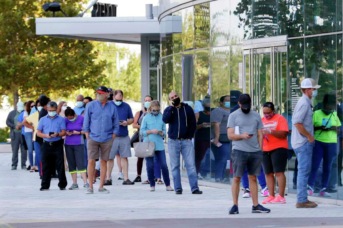 Voters wait in line outside of the Smart Financial Center as early voting begins Tuesday, Oct. 13, 2020 in Sugar Land, TX.
